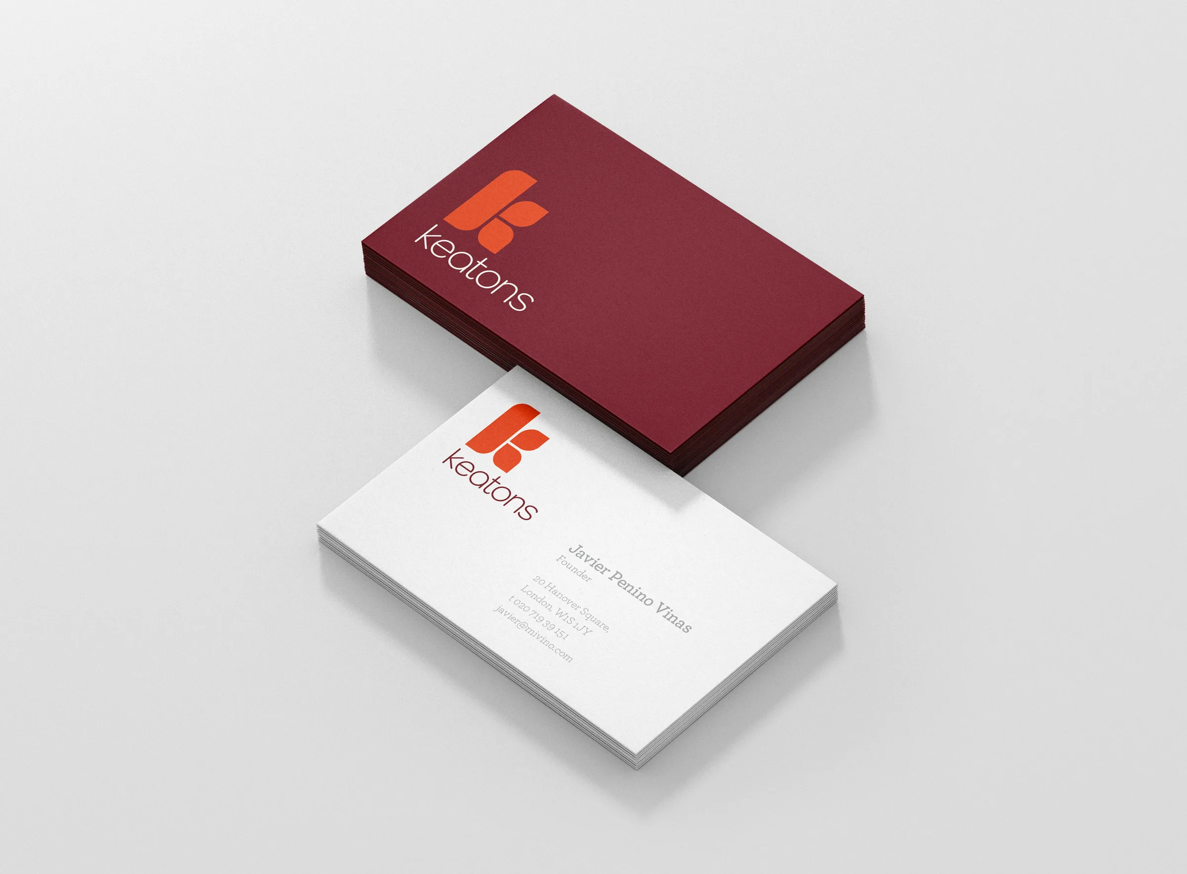 Two Keatons business cards, a burgundy card with the orange mark resting behind a white card with contact details