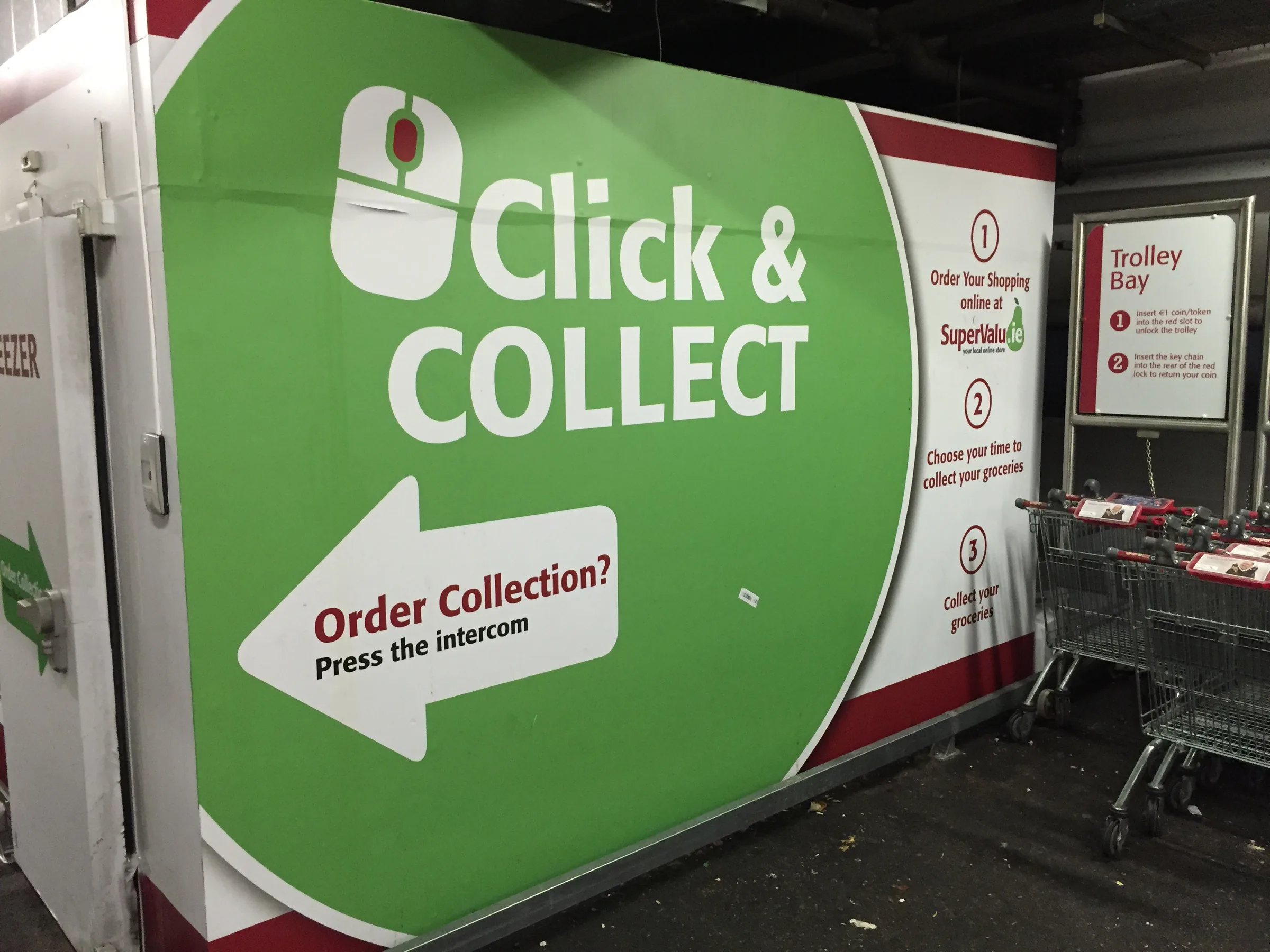 A green SuperValu click-and-collect station with an arrow pointing to order collection
