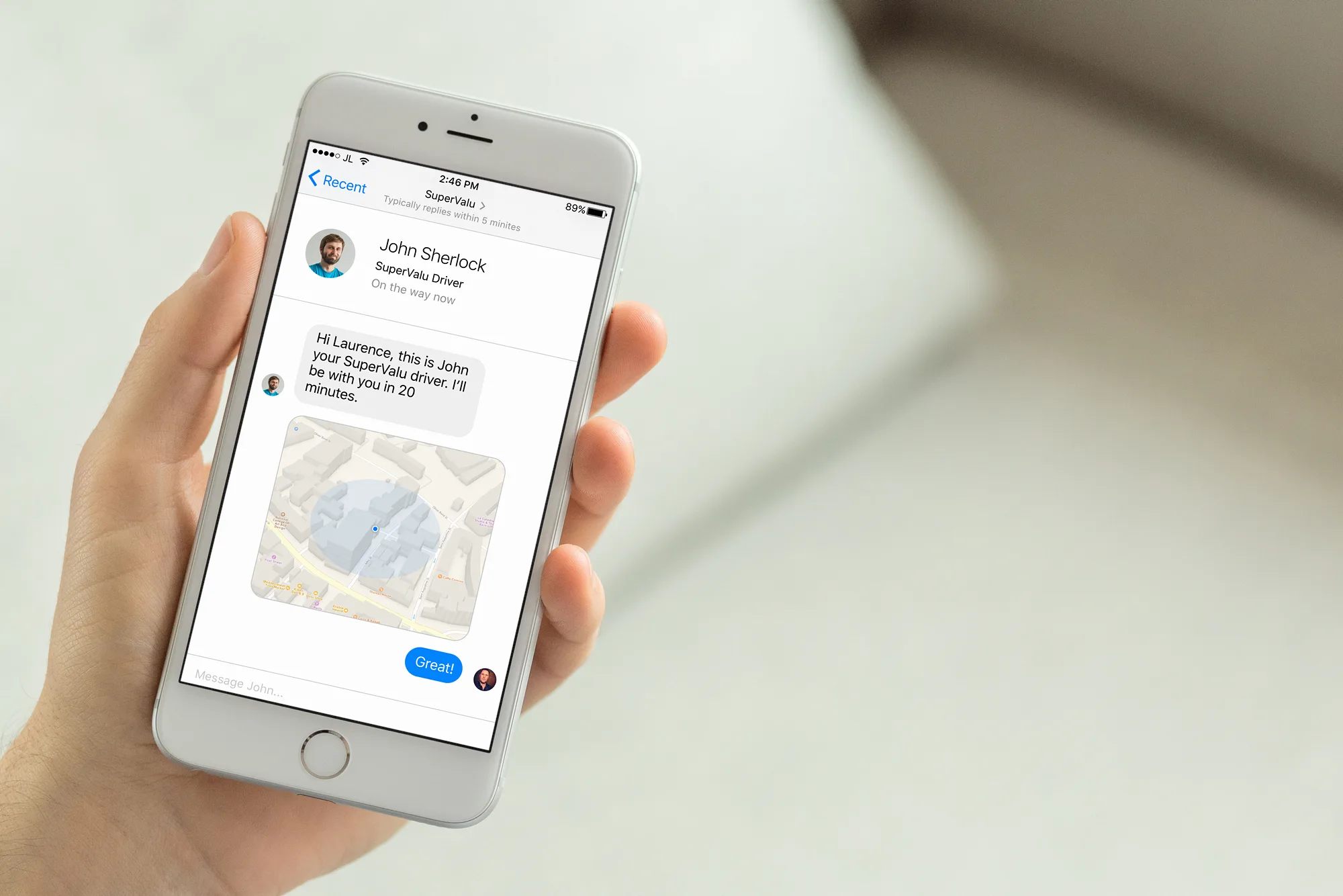 A hand holding a phone showing a message from a SuperValu driver with a map of their location