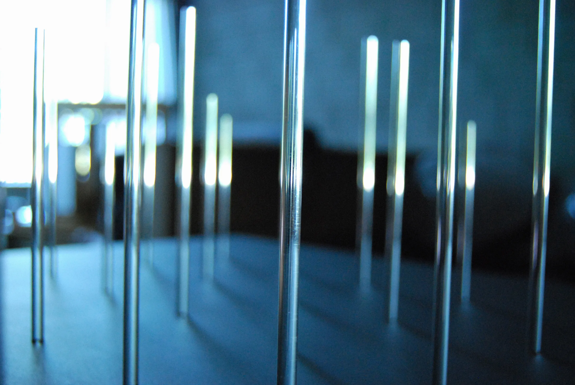 Close-up of metal pins at varying heights, lit in blue against a soft background