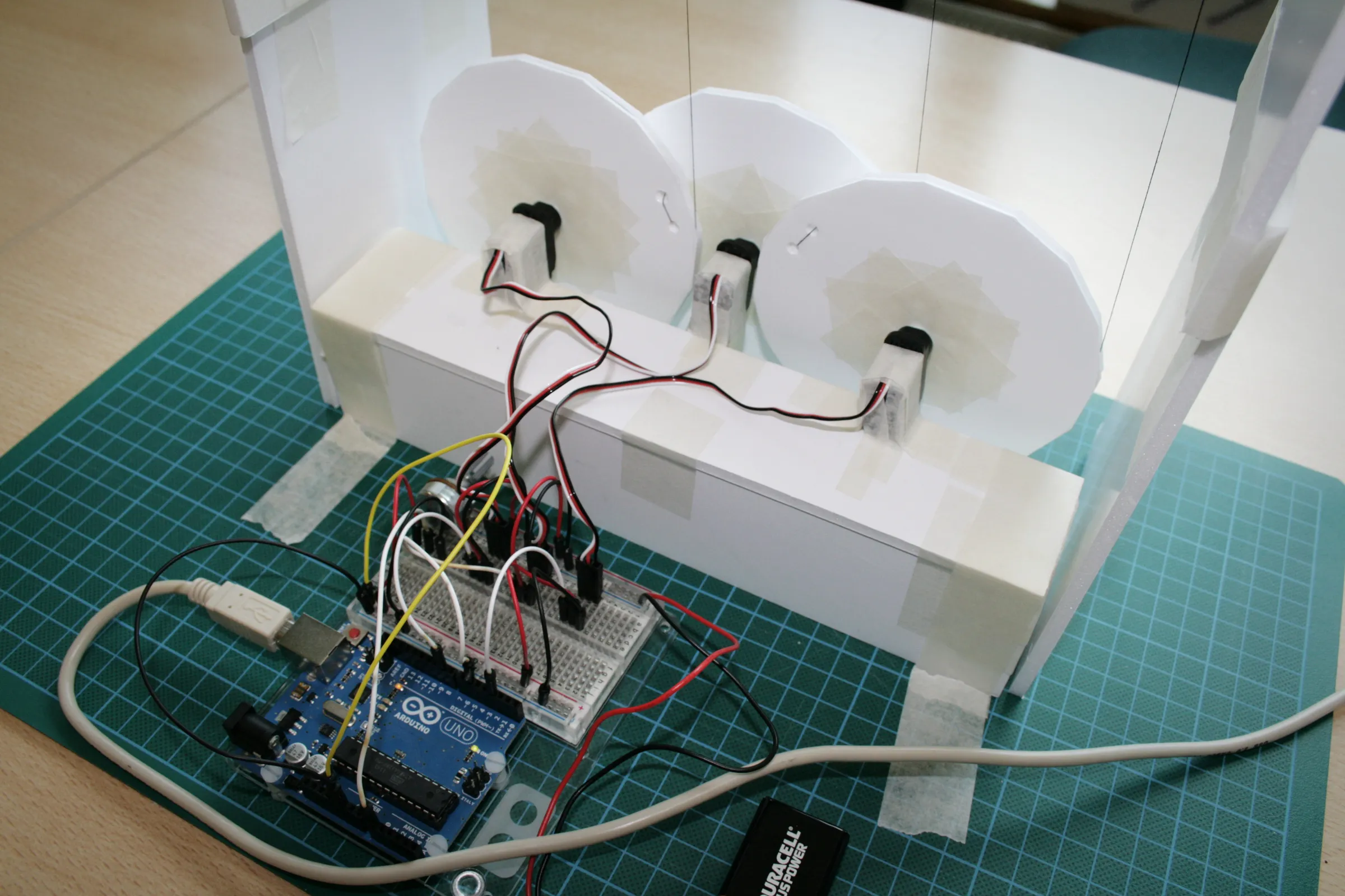 Inside the prototype, three card discs mounted on servos, connected to an Arduino and breadboard