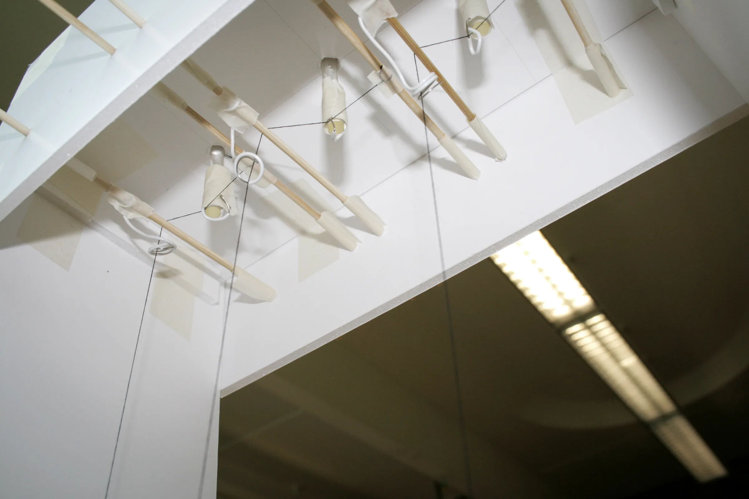 View up into the prototype showing threads running over wooden dowel guides toward the pins
