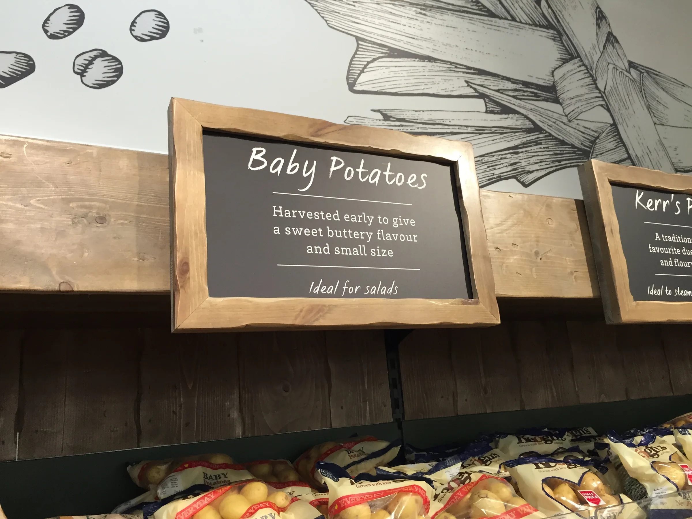A small framed sign for baby potatoes above a produce display